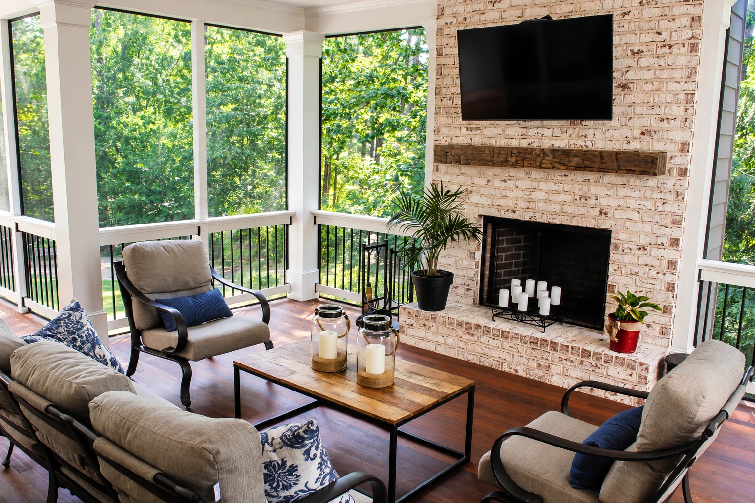 Enclosed deck converted into a sitting room with large windows, a brick fireplace, and upholstered chairs.