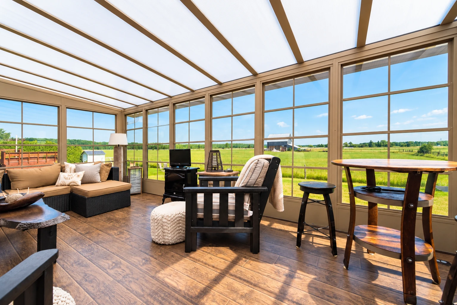 Sunroom with a translucent roof, tan framing, wood-look floor, and expansive views of open fields.